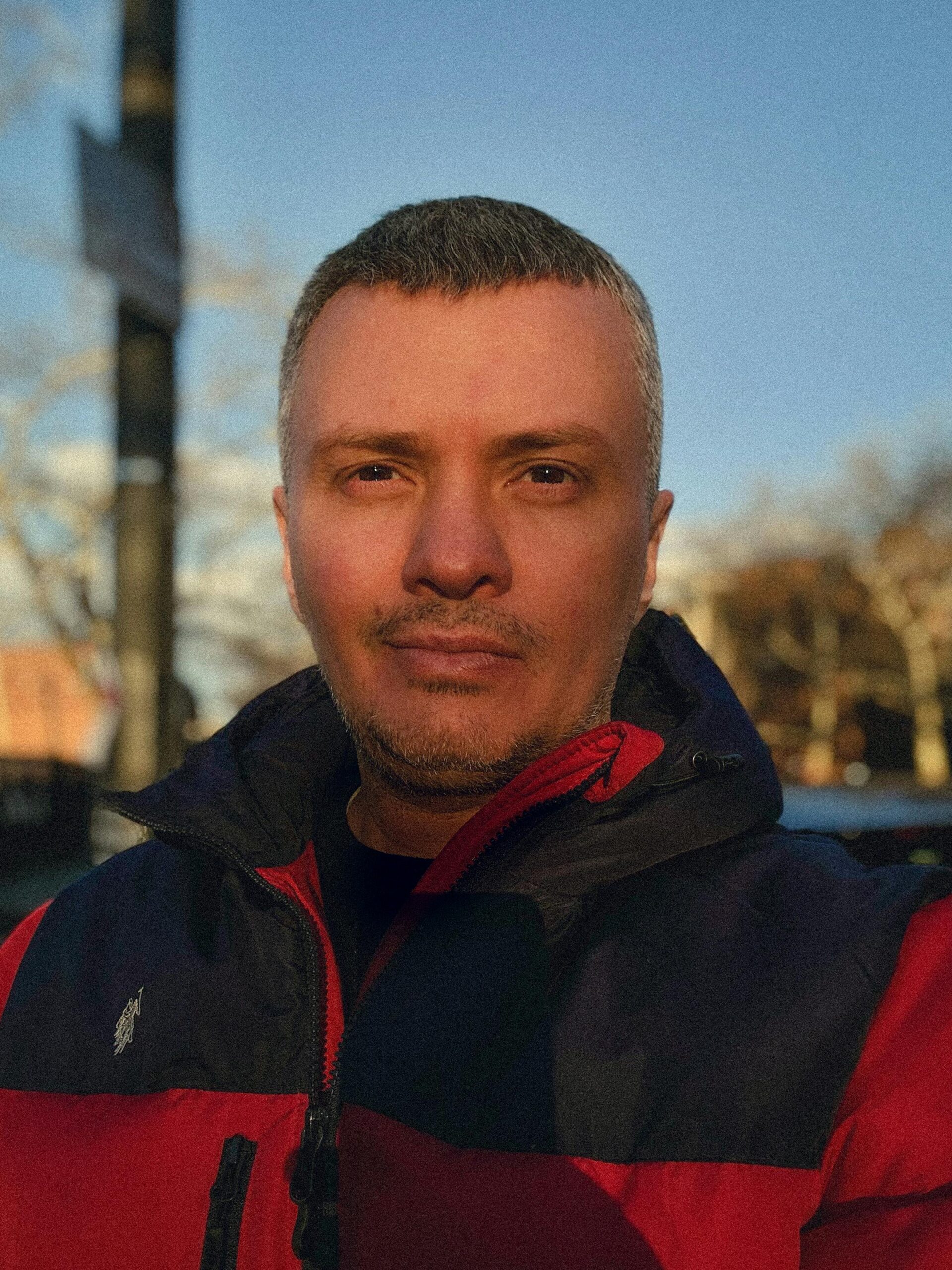 Outdoor portrait of a man wearing a red winter jacket, standing in New York City.