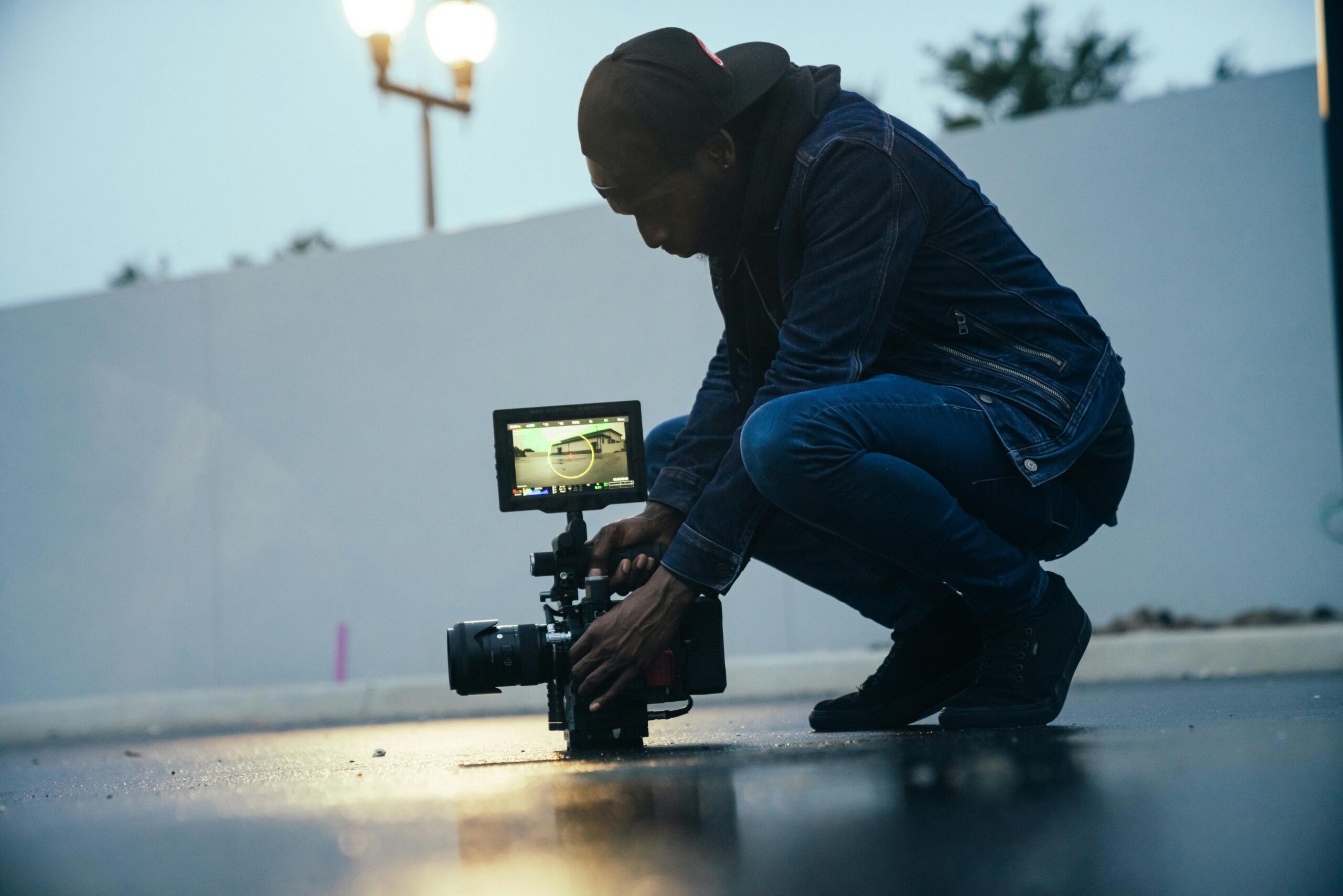 Capture of a videographer using a professional camera setup during an outdoor shoot at dusk.